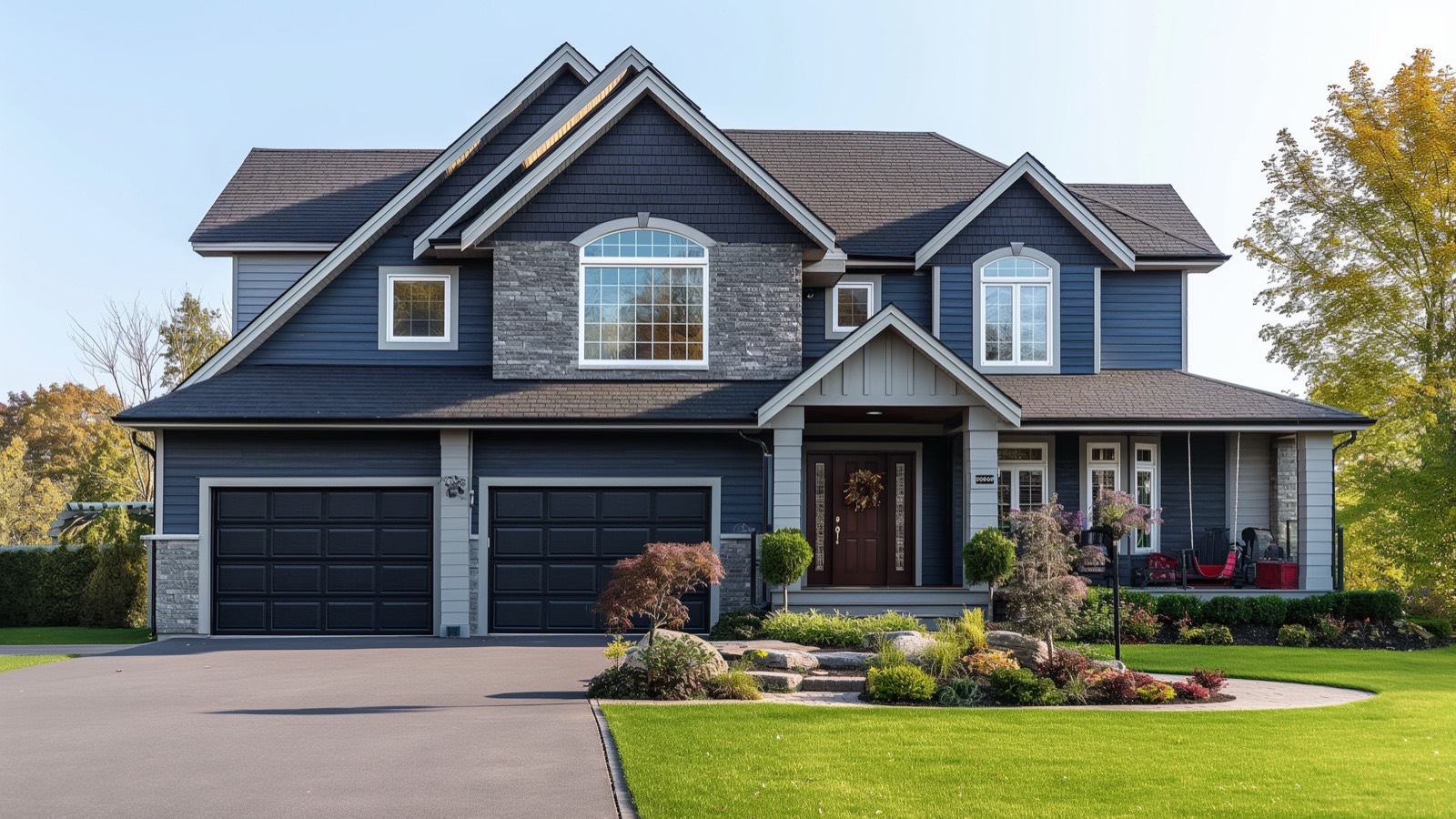 Large navy-blue Long Island home with stone accents, a multi-gable architectural shingle roof and a three-car garage