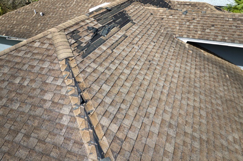 Roofer repairing storm-damaged shingles on a Long Island home